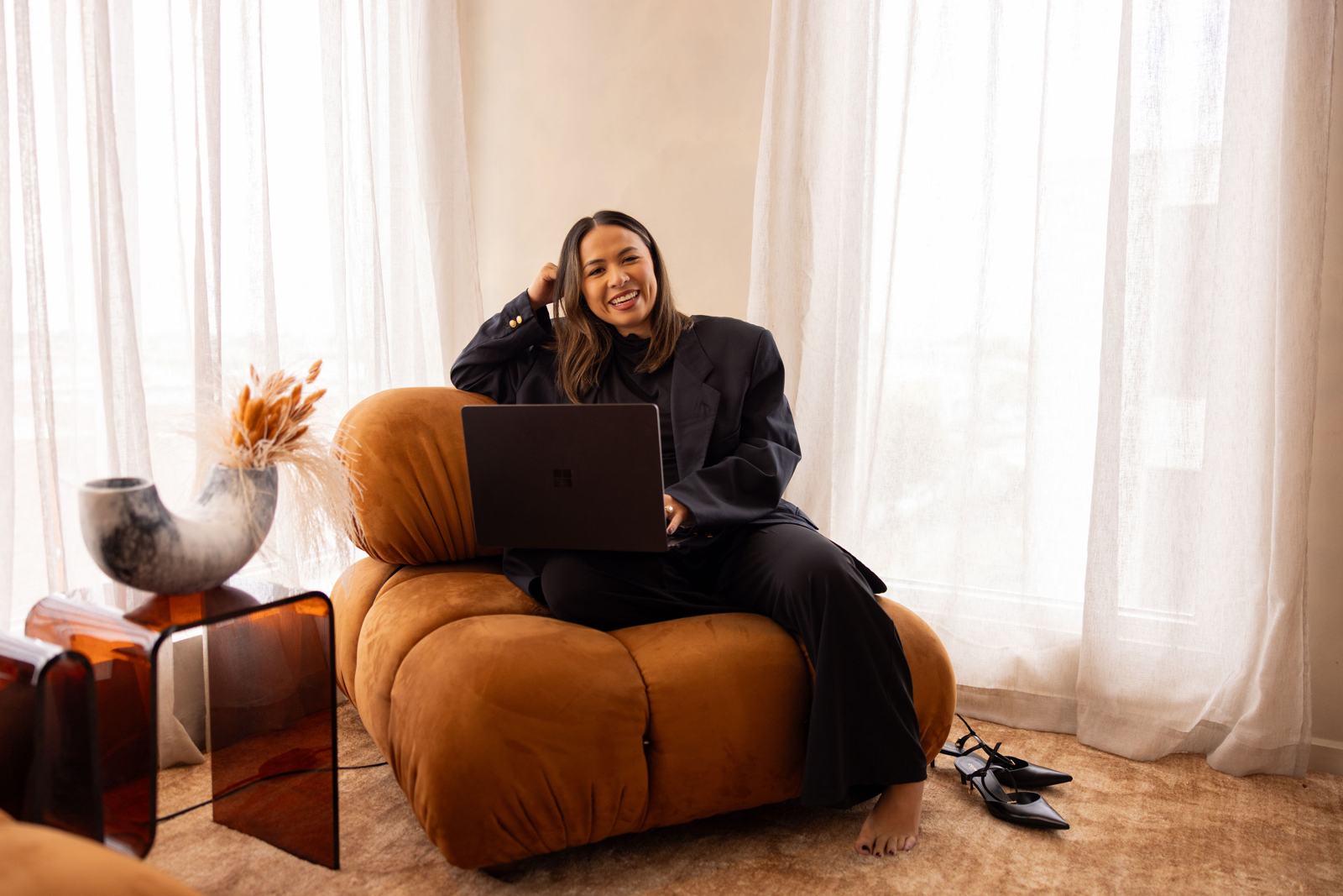 Stephanie Nguyen on an orange velvet chair with her laptop